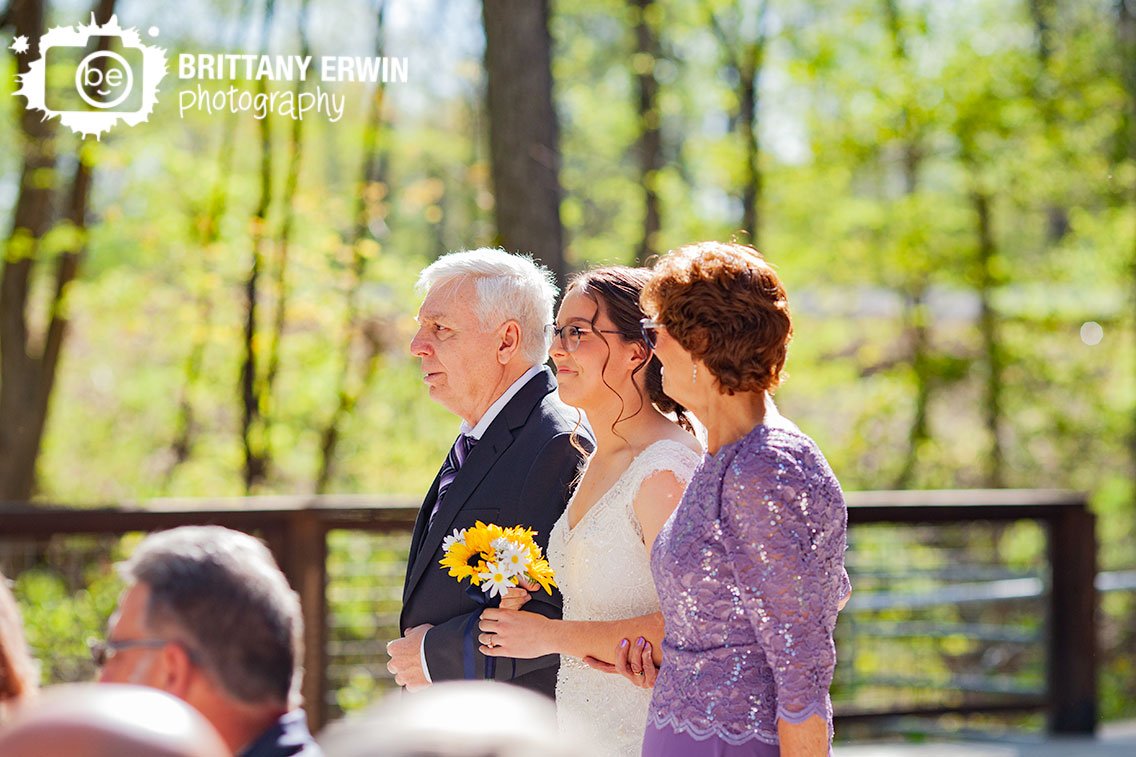 bride-walking-down-aisle-with-parents-outdoor-ceremony.jpg