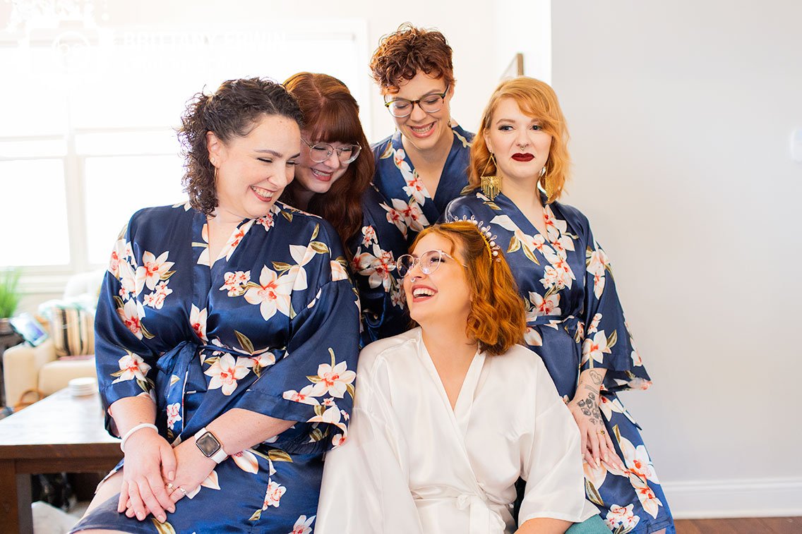 bride-with-bridesmaids-matching-robes-in-chair.jpg