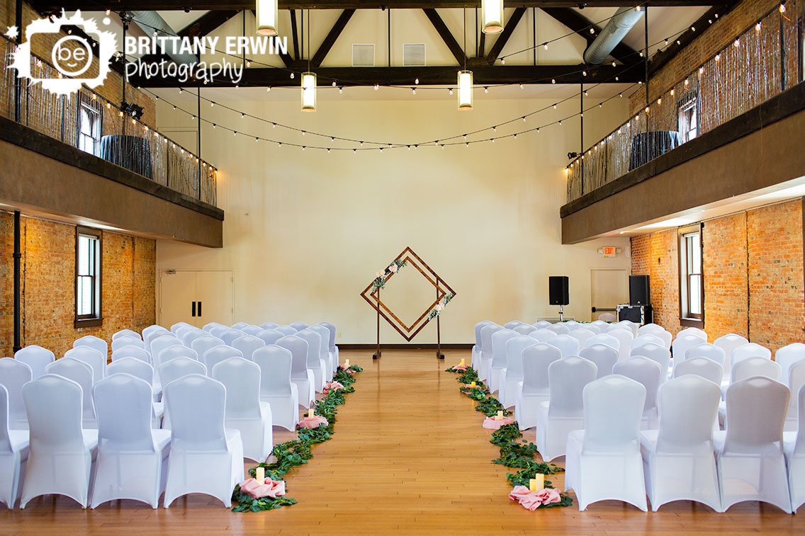 Indianapolis-wedding-ceremony-venue-white-covered-chairs-with-greenery-and-candle-lined-aisle.jpg