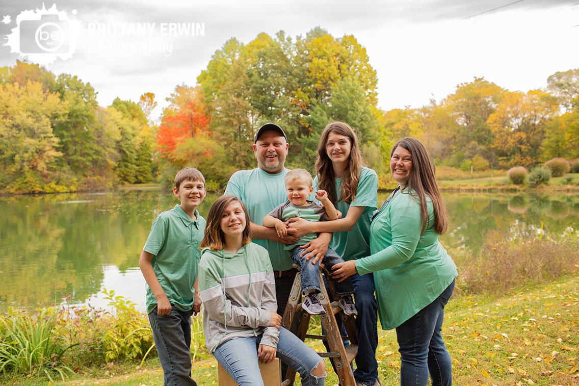 Family-group-portrait-outside-by-lake-with-fall-trees.jpg
