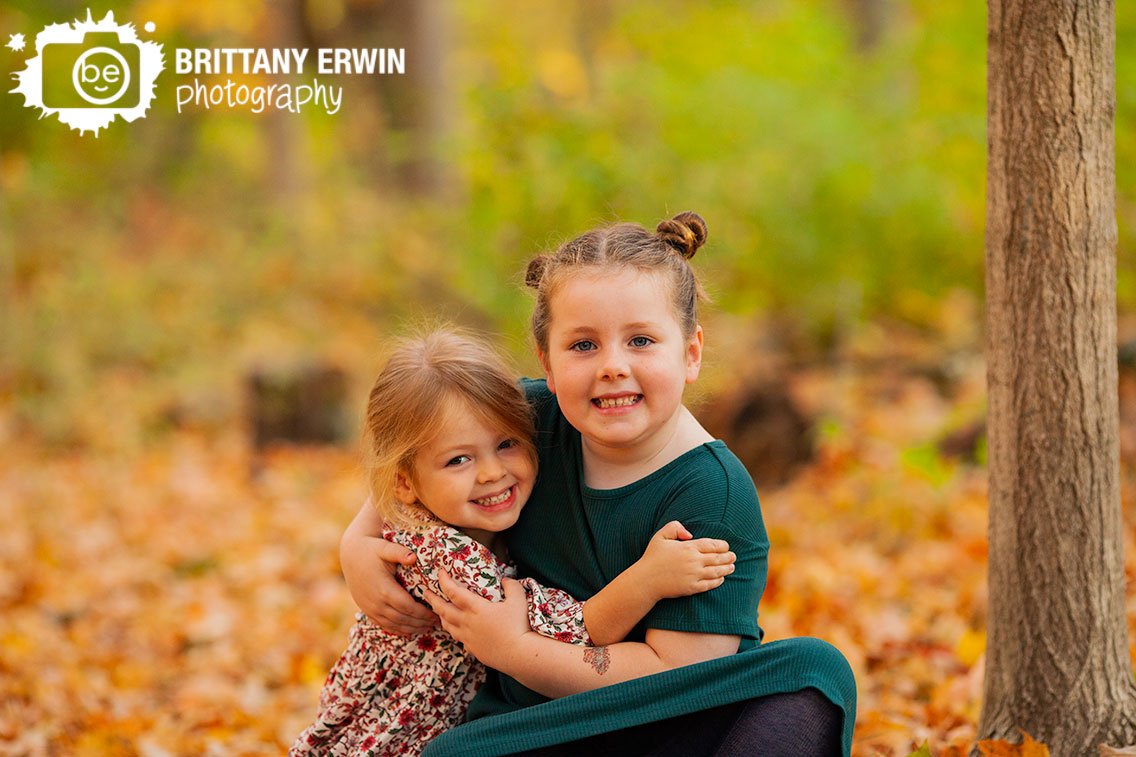 sisters-hugging-outdoor-portrait-photographer-fall-leaves.jpg