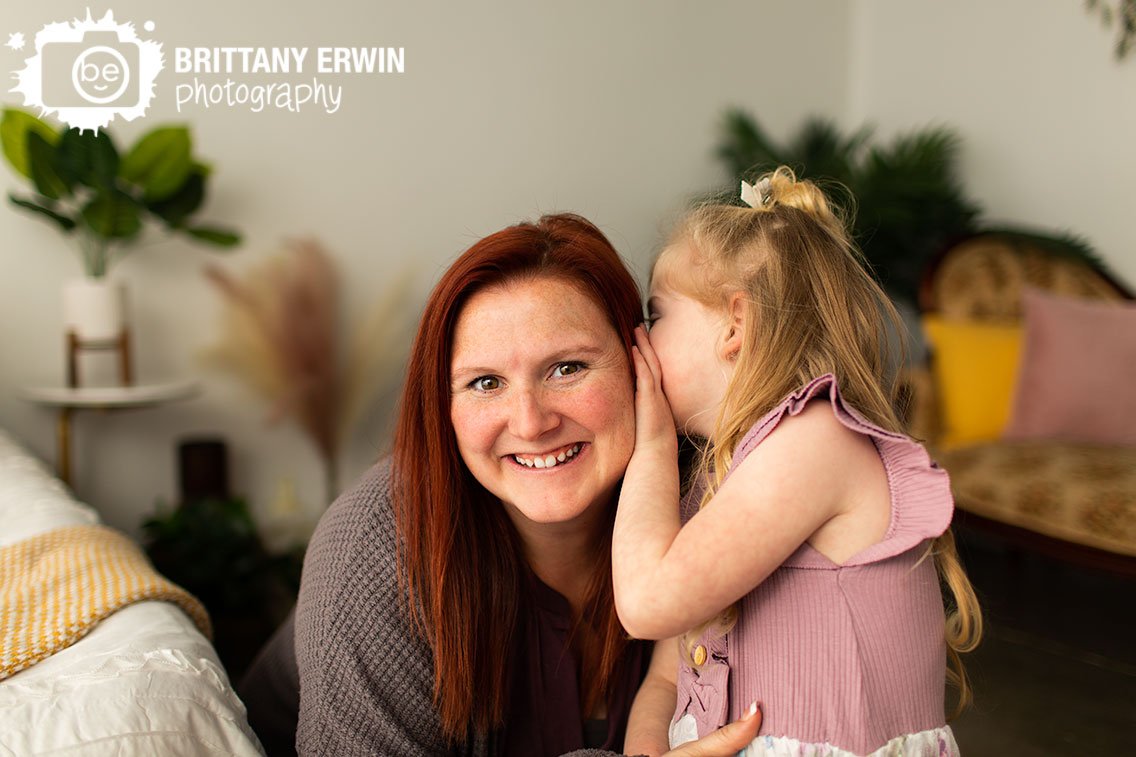 Mother-daughter-portrait-with-little-girl-wispering-in-moms-ear.jpg