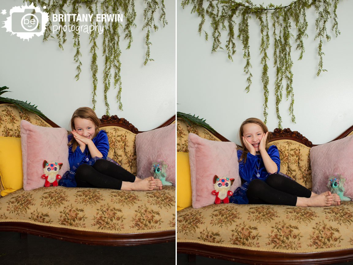 Indianapolis-portrait-photographer-girl-on-antique-couch-with-stuffed-animals-and-greenery-wall-hanging.jpg