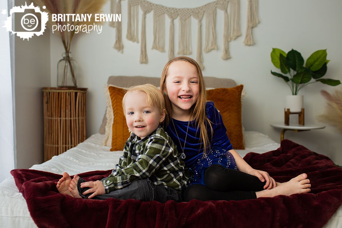 Indianapolis-siblings-portrait-on-bed-with-macrame-wall-hanging-fuzzy-burgundy-blanket-with-sparkle-dress.jpg