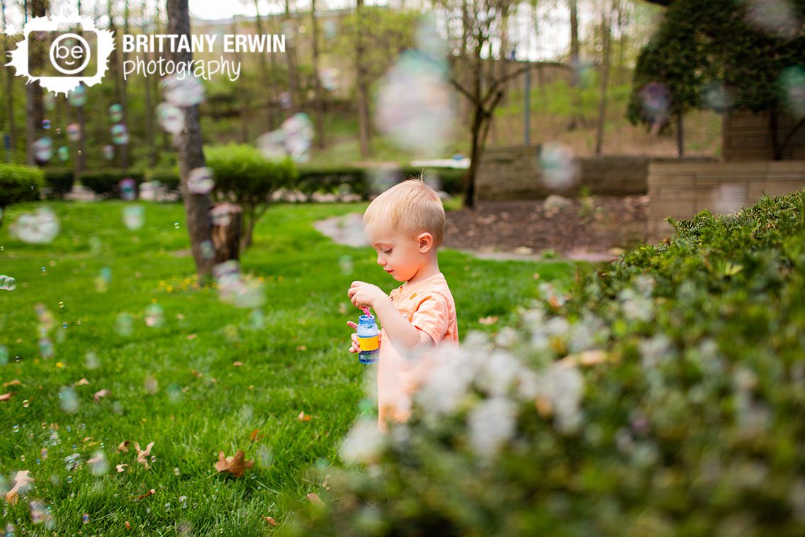 Indianapolis-spring-portrait-photographer-boy-playing-with-bubbles-at-park-with-stone-wall.jpg