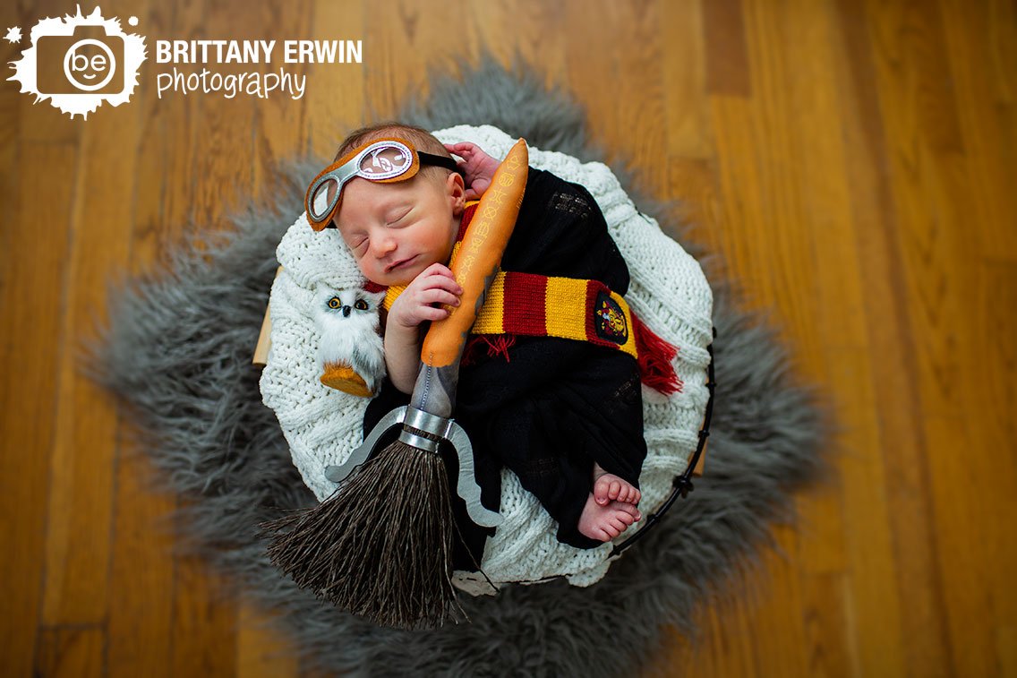Harry-Potter-newborn-portrait-photographer-broom-with-flying-goggles-tiny-hedwig-and-griffindor-scarf-sleeping-boy-in-basket.jpg