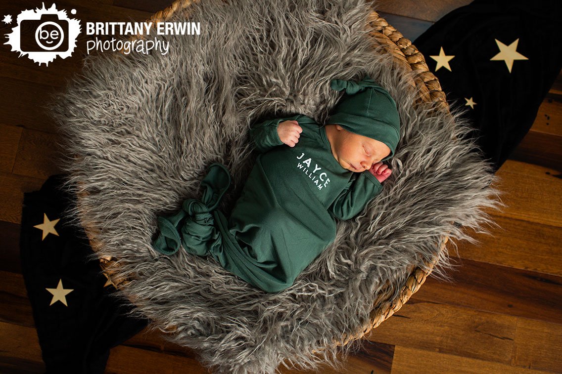 Baby-boy-with-custom-tie-bottom-onesie-and-sleeper-hat-in-basket-with-moon-pillow-and-wooden-stars.jpg