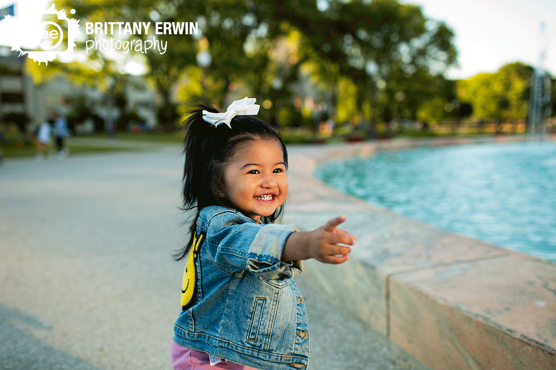 Indianapolis-portrait-photographer-first-birthday-girl-by-fountain-downtown-Indianapolis.gif
