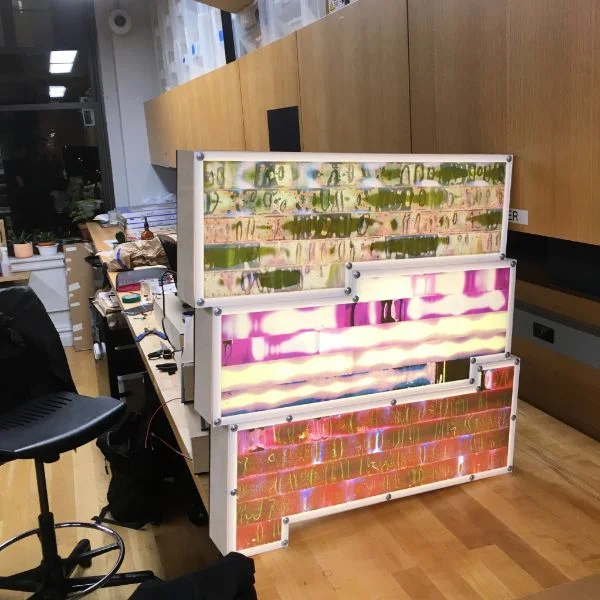 These light boxes are actually calendars that reflect his emotional state throughout the past year. The brilliant coloring on the face is created using strips of film.