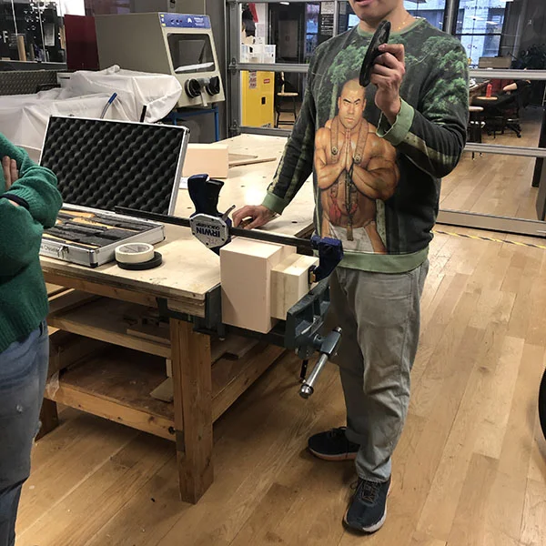 Chester is explaining the basics of the lathe set up and operation as it is the first time for both students. They're working on their prototypes for their MoMA design store pitches.