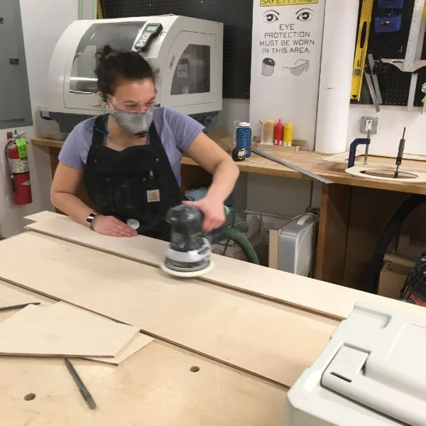 The notes they leave behind will then be sent to the NYC mayor's office. Hannah ripped all of the wood on the table saw with the help of VFL staffer Elizabeth and fellow Products of Design second year Carly. She is using the Festool orbital sander to prep the pieces and keep the shop clean.