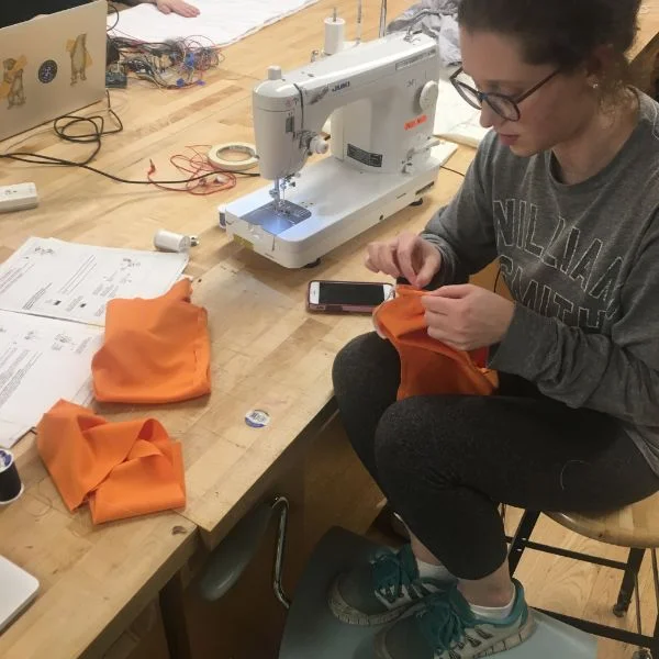 MFA Products of Design second year Carly Simmons is in the lab today working on a nursing blouse for mothers in the workplace. She is using one of the shop's sewing machines and ancillary sewing supplies in order to modify an existing blouse with some knit fabric and elastic she sourced herself.
