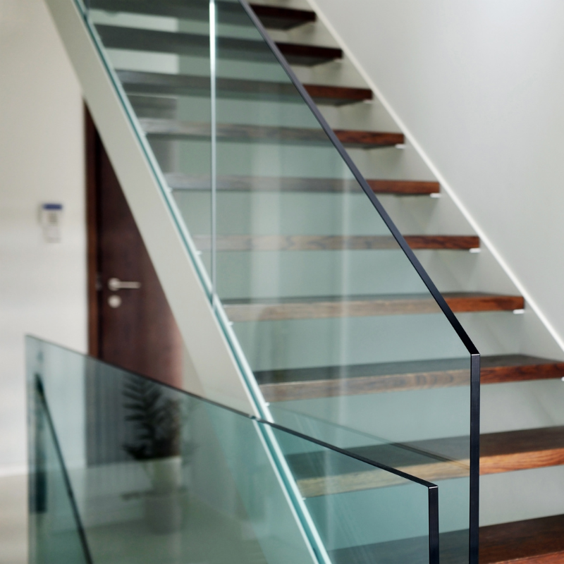 Interior view of a staircase with wooden steps and glass railings, in a modern home.