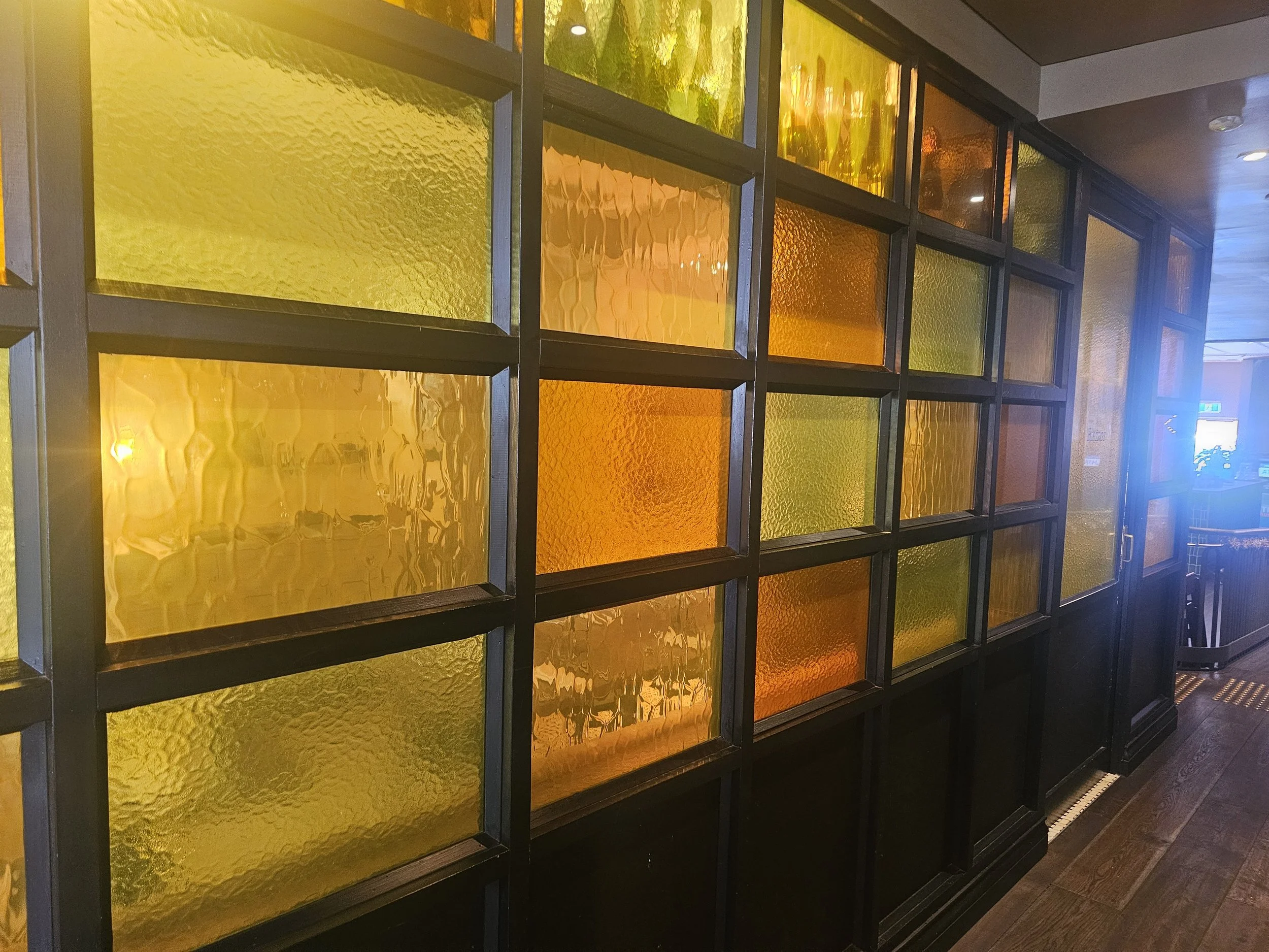 Colorful textured glass window panes in black frames inside a building.