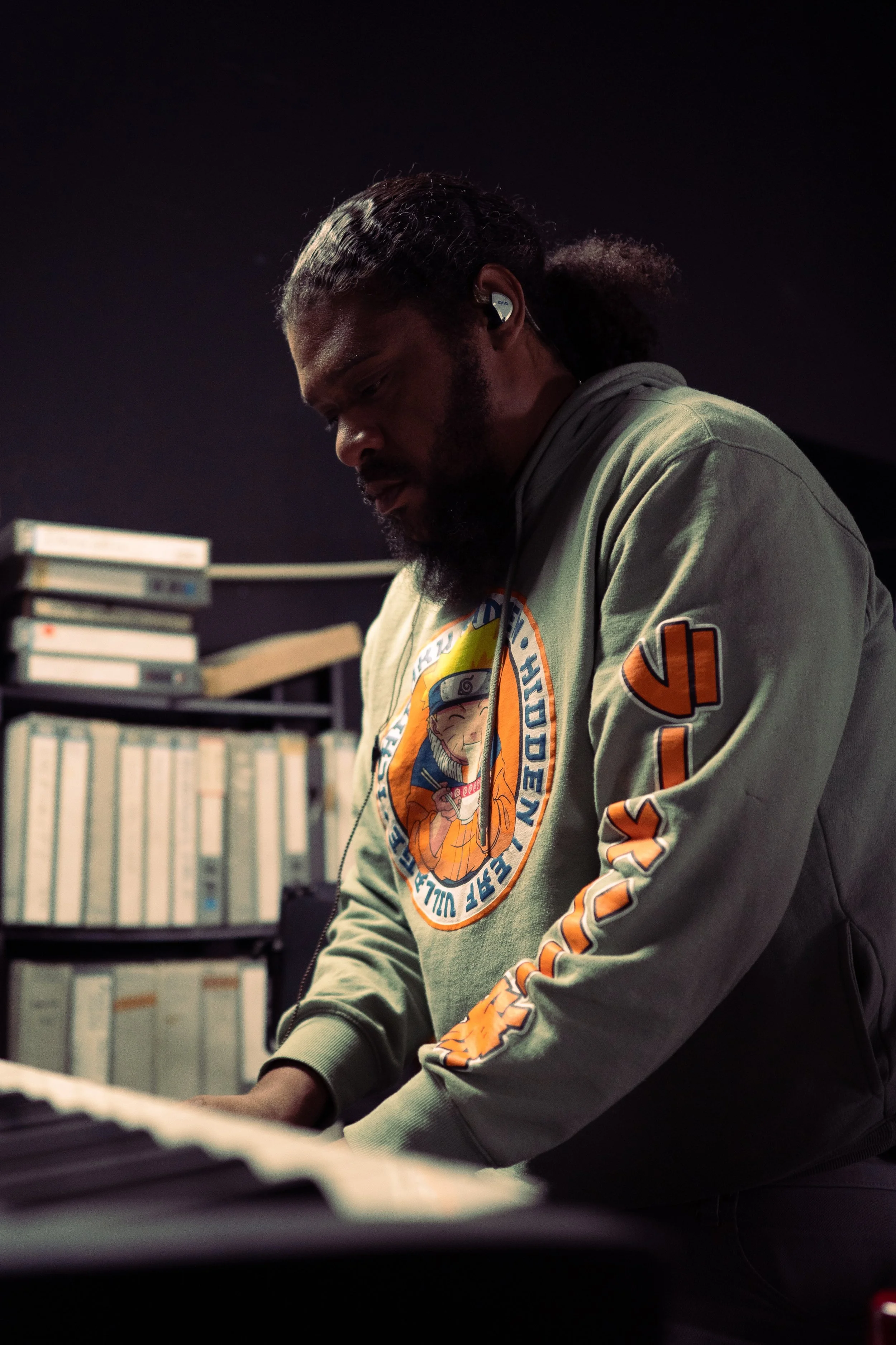 A man with headphones playing a keyboard in a music studio.