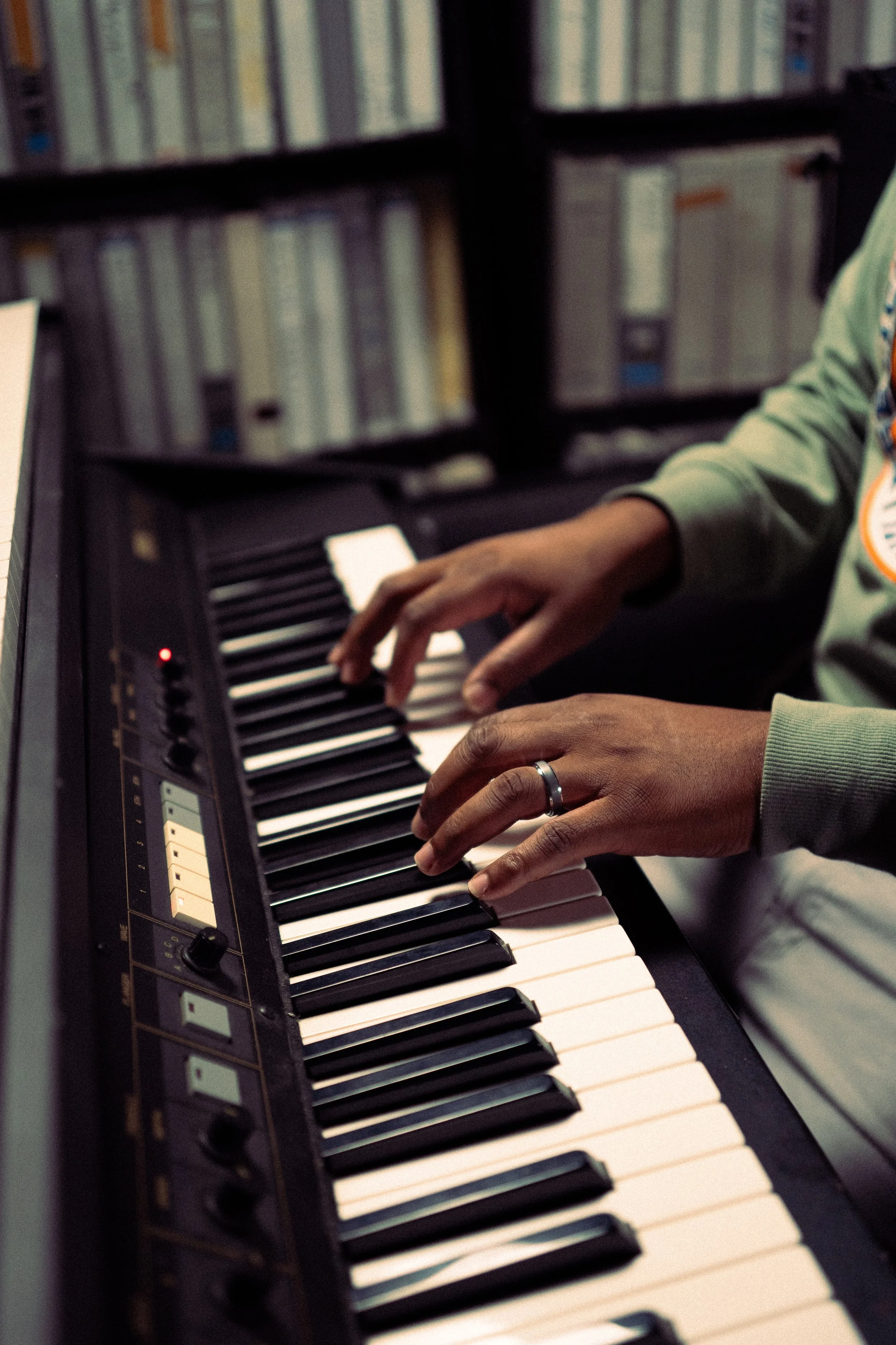 Person playing a digital piano with a library in the background.