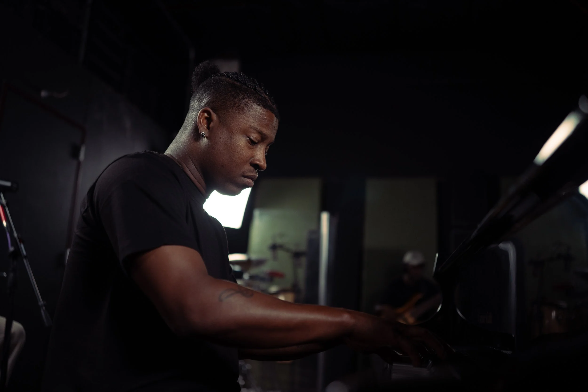 A woman playing a piano in a dark room with studio lighting.