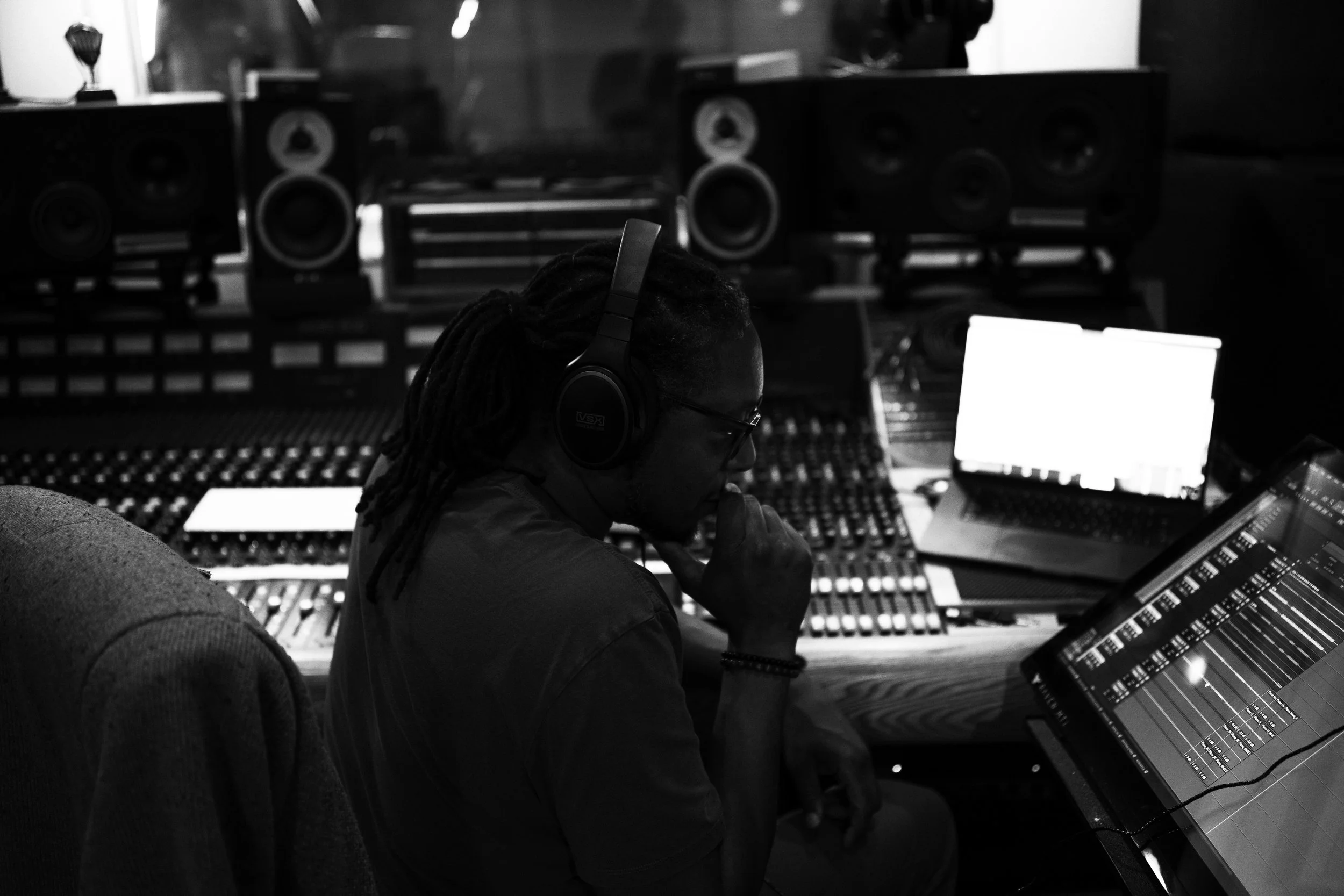 A person wearing headphones working with audio equipment in a music studio.