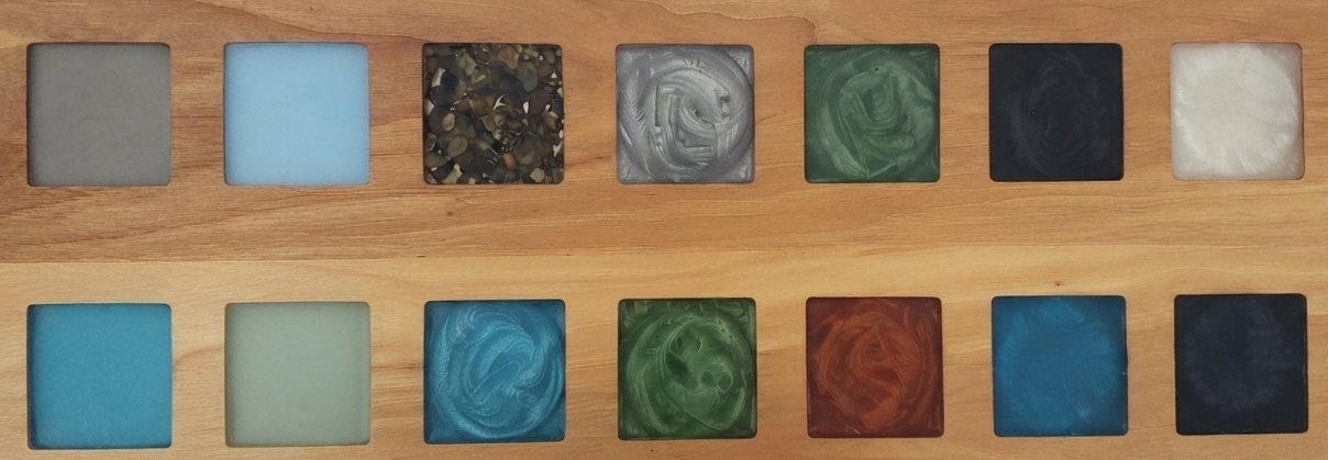 A wooden board with two rows of six square inlays, each containing different marbleized patterns and colors.