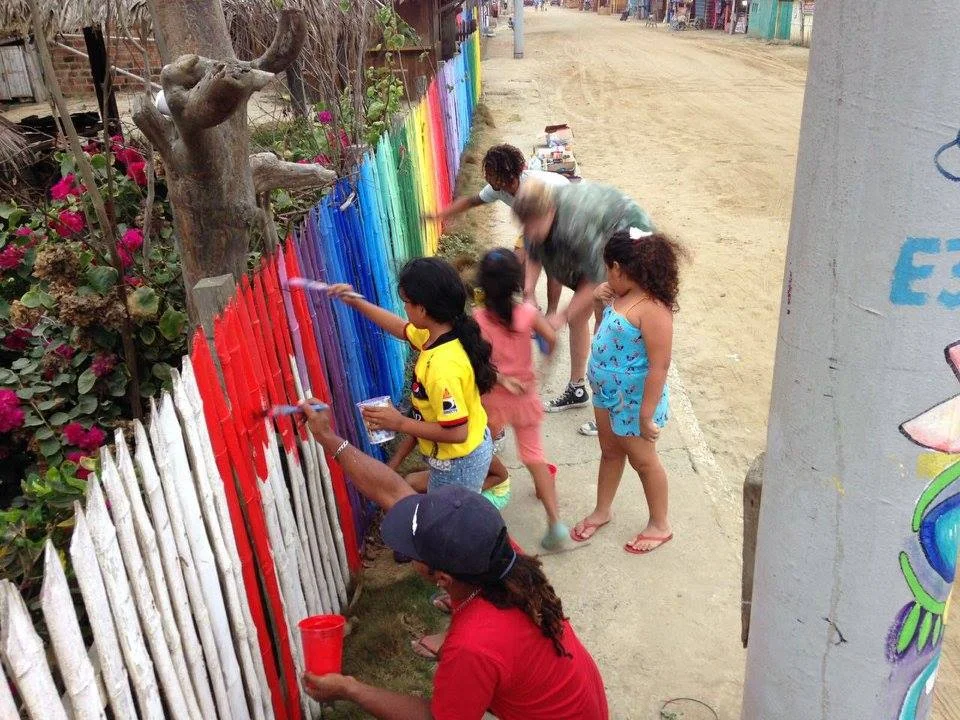 Children of Canoa work together to use left over paint from the festival to bring some color to the town's bamboo fences.