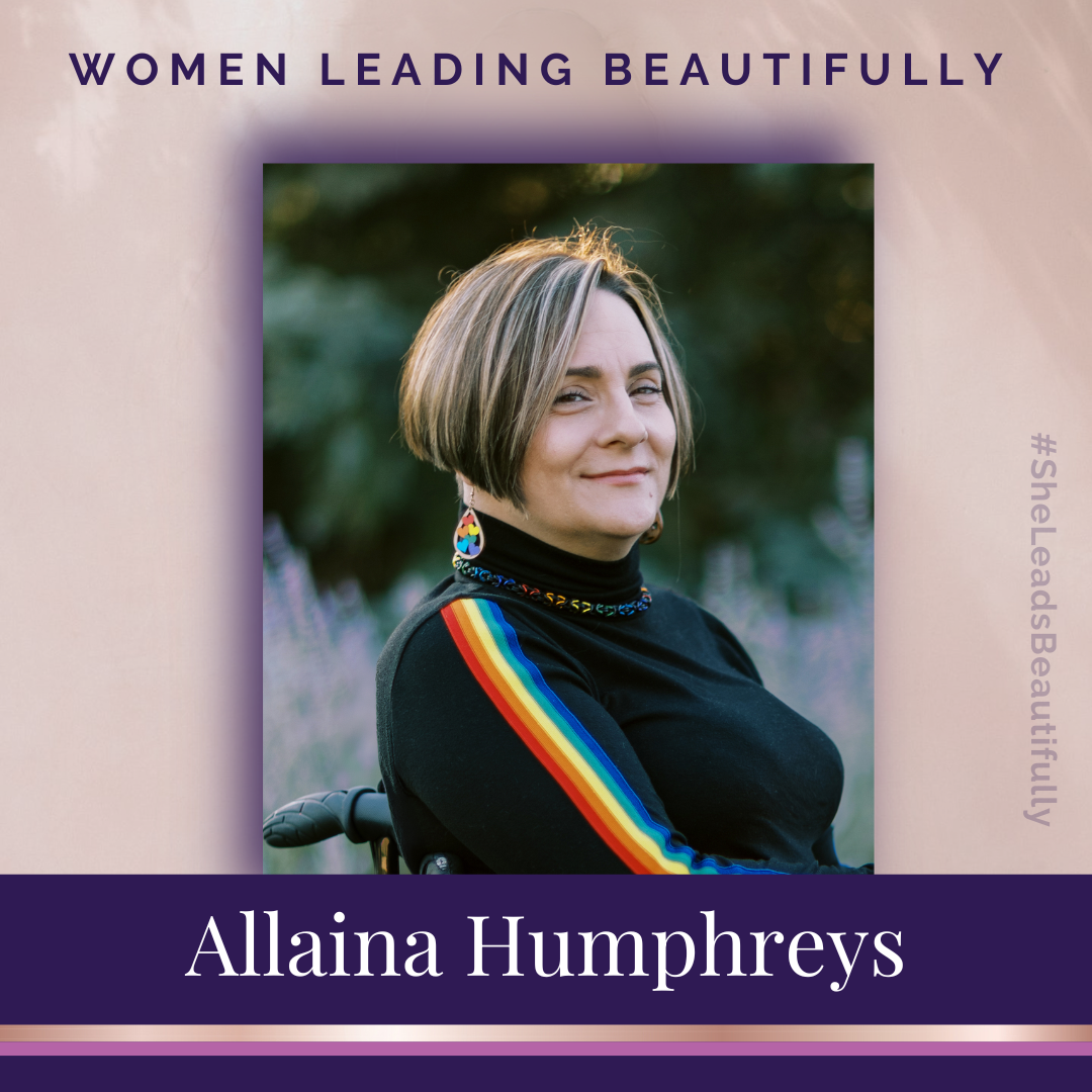 Women Leading Beautifully - Allaina Humphreys sitting in her wheelchair outdoors. Wearing black turtleneck with a rainbow stripe sleeve. Also wearing rainbow earring and necklace.- #SheLeadsBeautifully