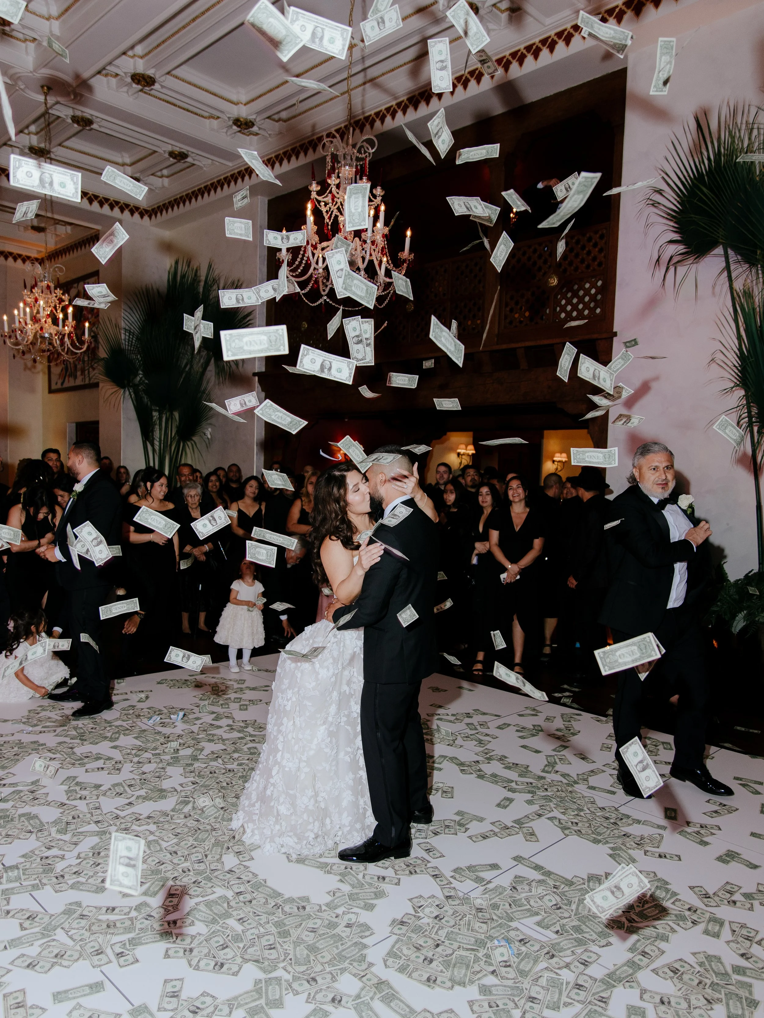 Bride and Grooms first dance as dollar bills rain down across the Great Room. Guests watch in the background while kids gather the money