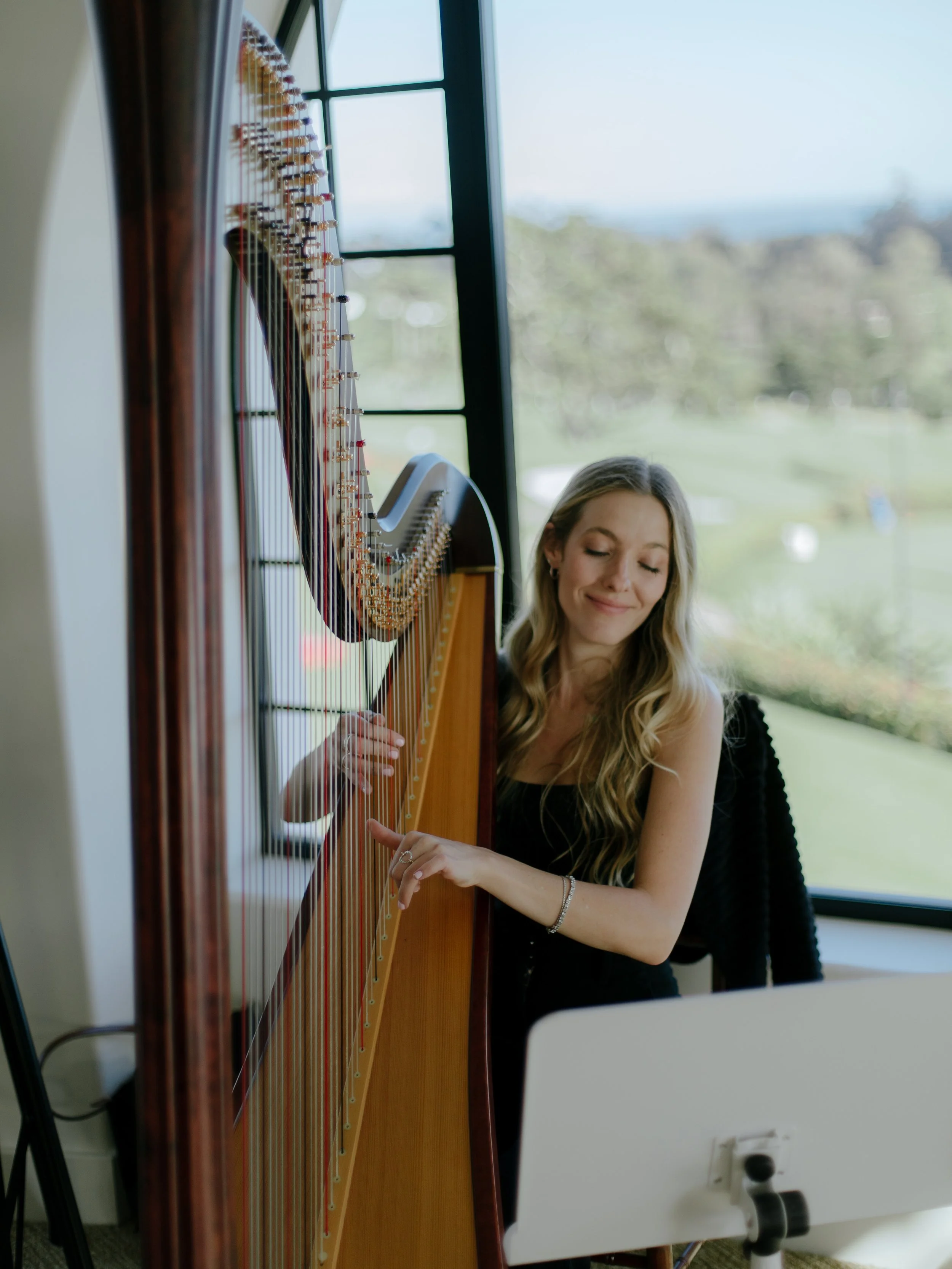 Harpist Ginger Rose performs beside a window overlooking the Montecito Club grounds