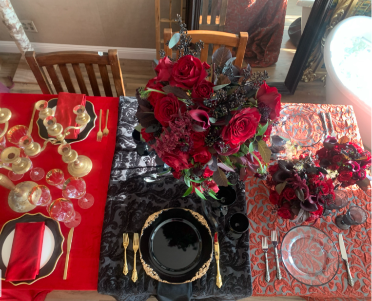 Three tabletop mock-ups side by side in red, black damask and coral linens, each set with flatware, black and glass chargers and deep red rose centerpieces