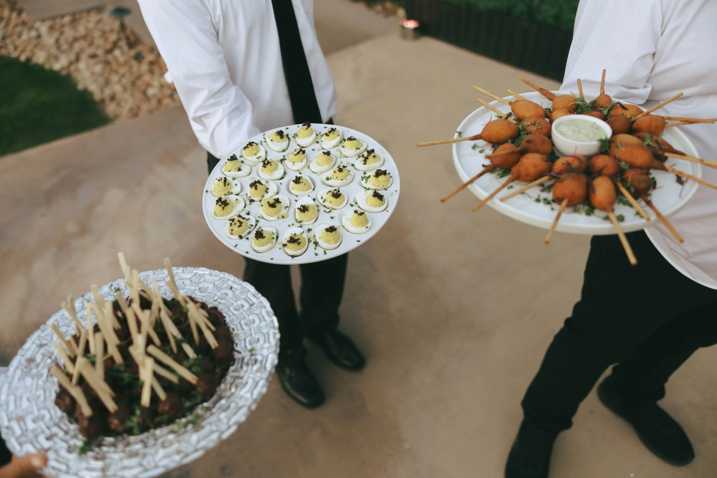 Servers passing trays of deviled eggs with caviar and skewered shrimp during the reception