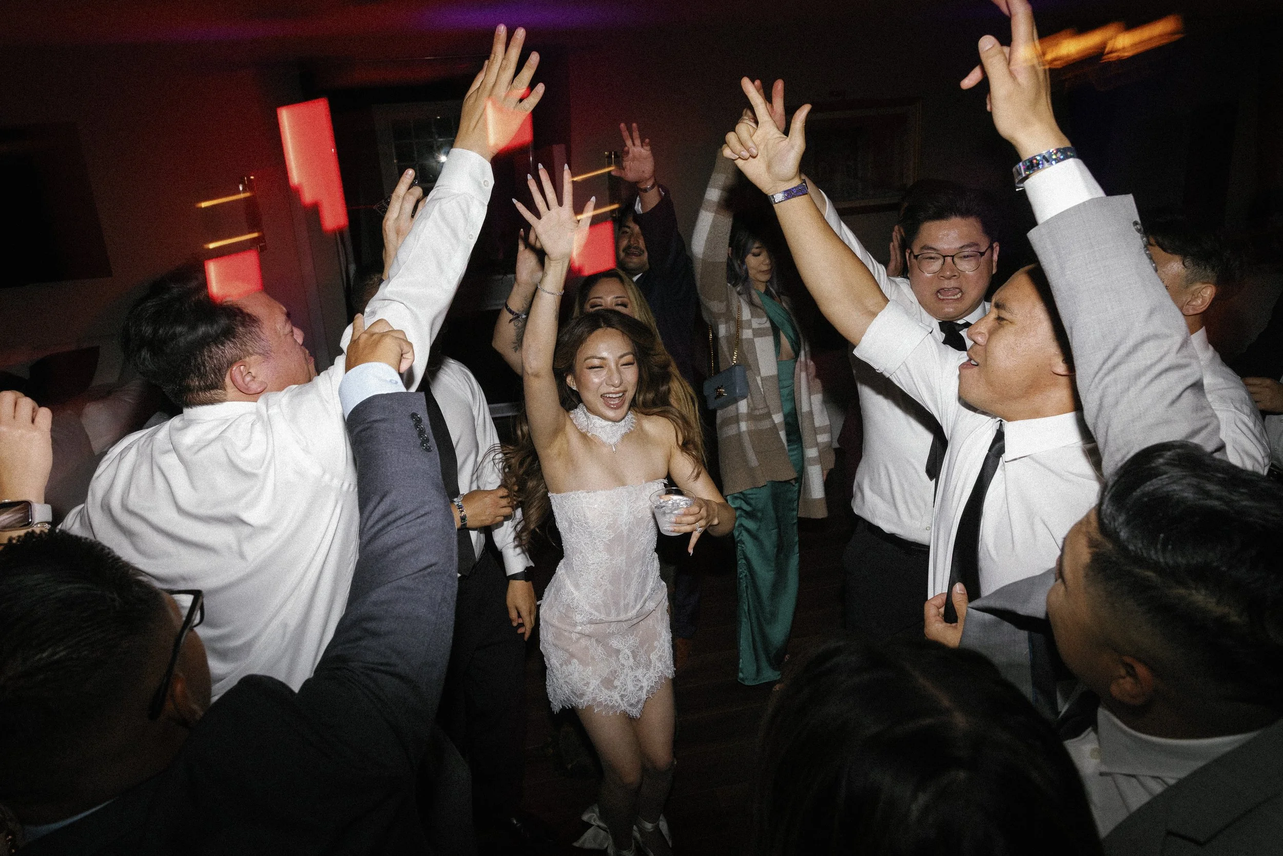 Bride in a short lace reception dress on the dance floor as guests celebrate at the after-party.