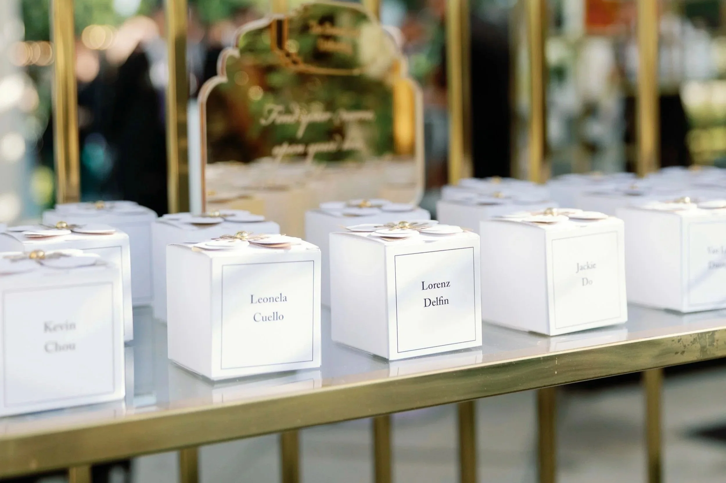 Sugarfina blind box escort display with guest names on a gold mirrored table.