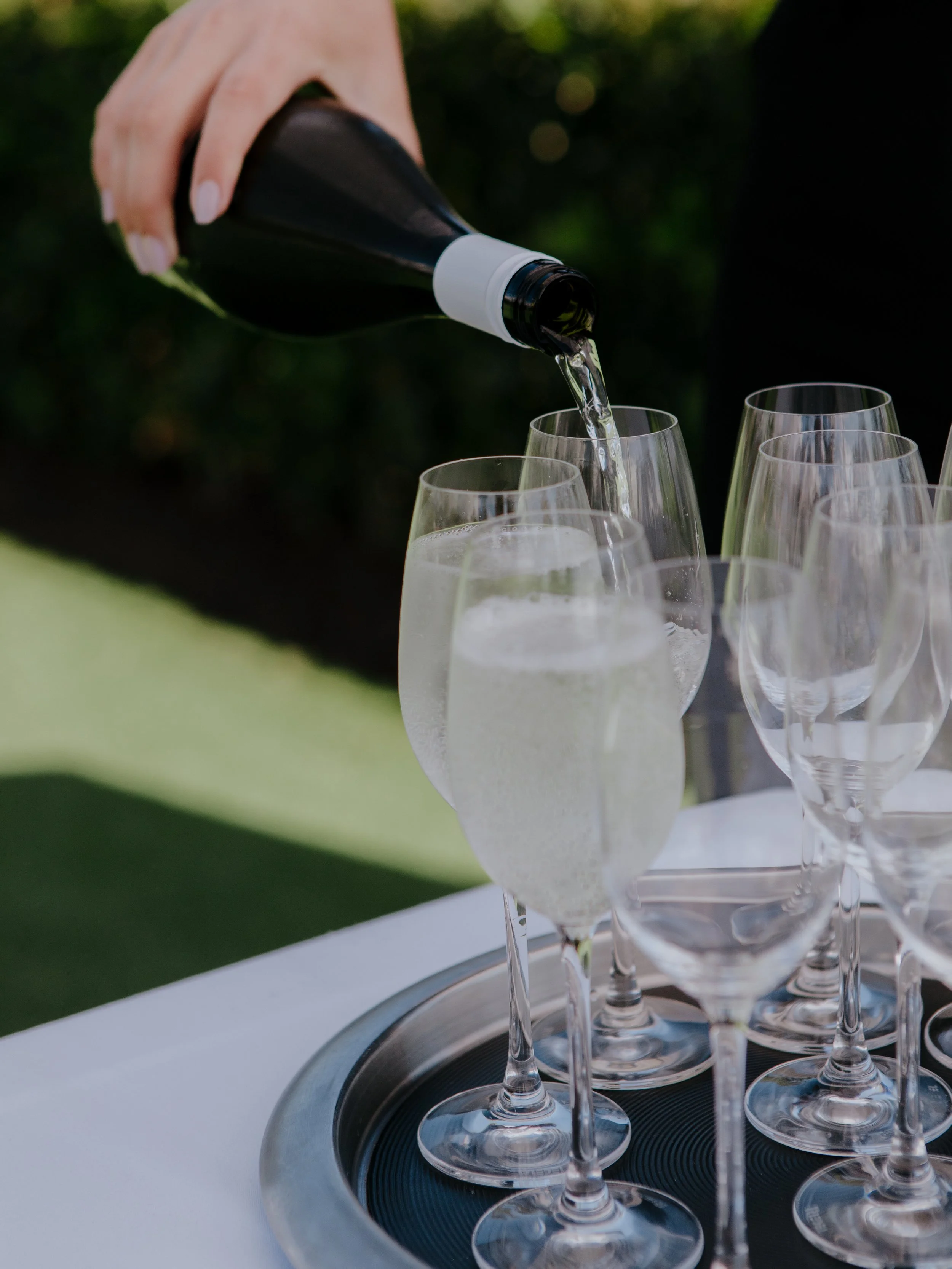 Champagne poured into glasses on a silver tray for arriving ceremony guests