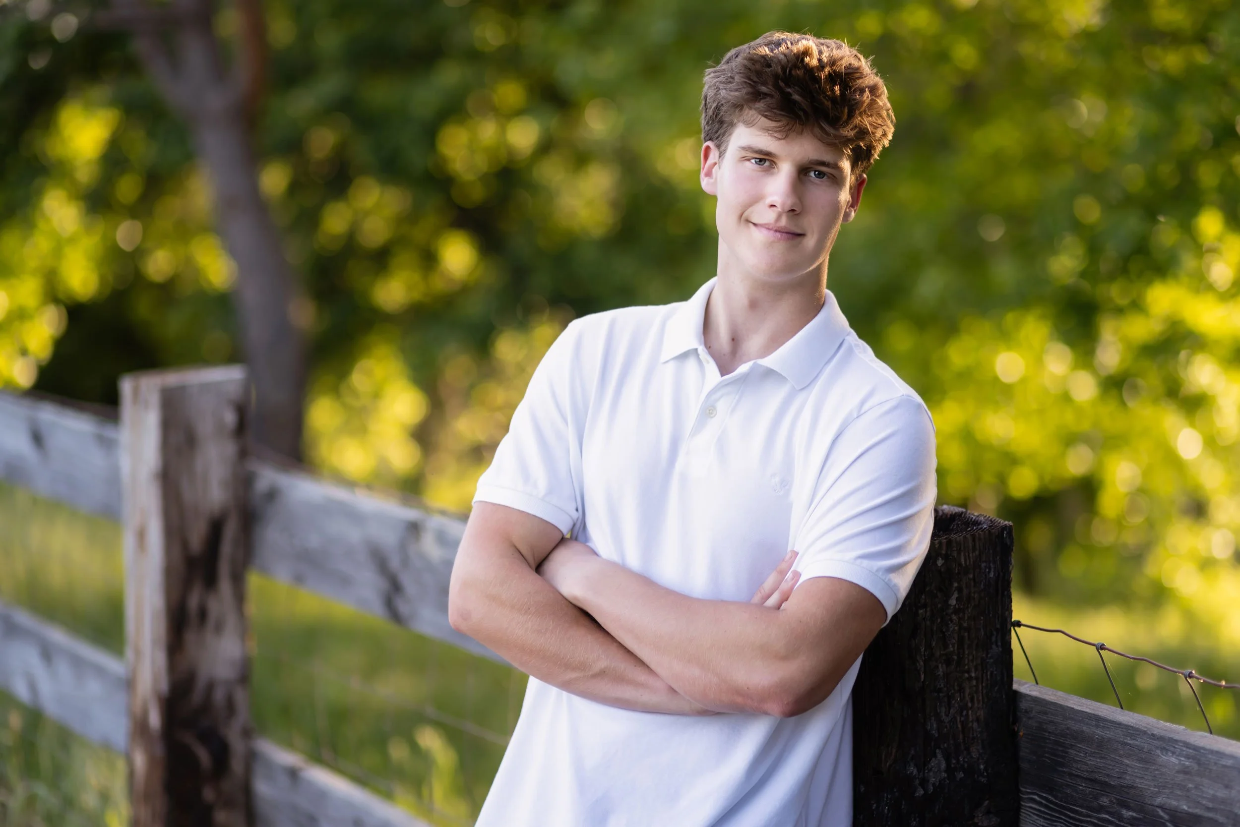 Senior Nick leans against a split-wood fence at Bywater Hollow Lavender Farm in Lincoln, California in the spring of 2026