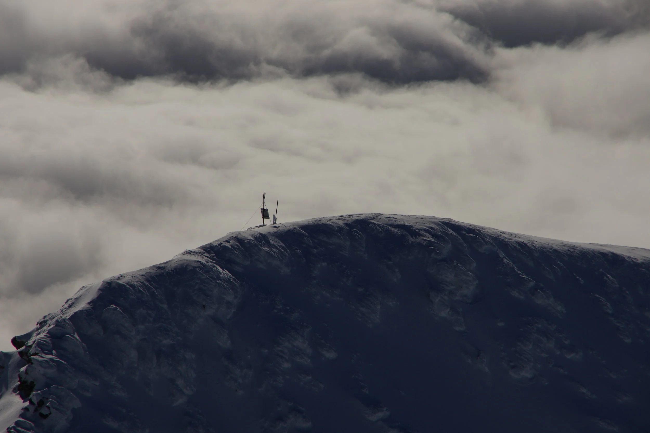 High-mountain AWOS weather station stands guard over a snow ridge