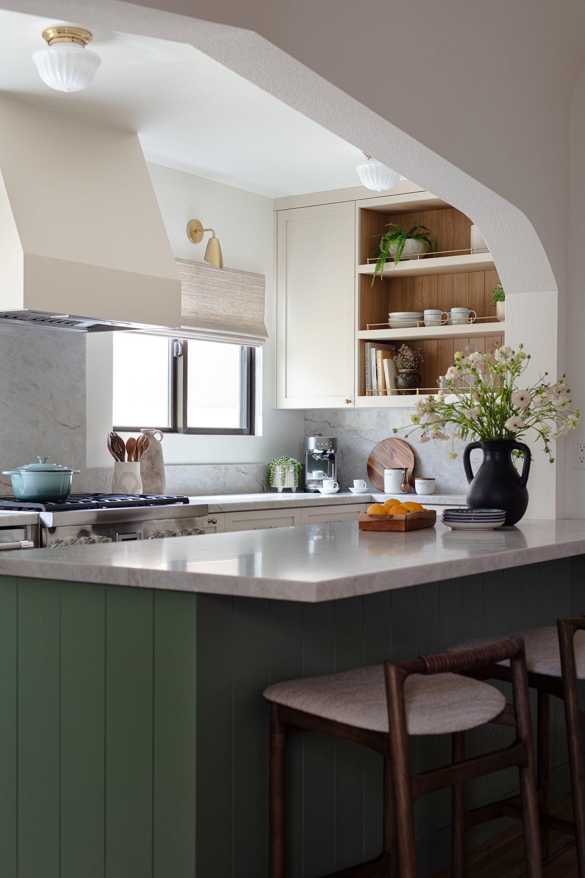 sage green cabinets, linen roman shades, brass hardware, gallery rail, cream cabinets, vintage lighting, taj mahal stone, aged brass light fixtures, aged brass, vintage kitchen, kitchen renovation, white oak wainscot, ivory cabinets