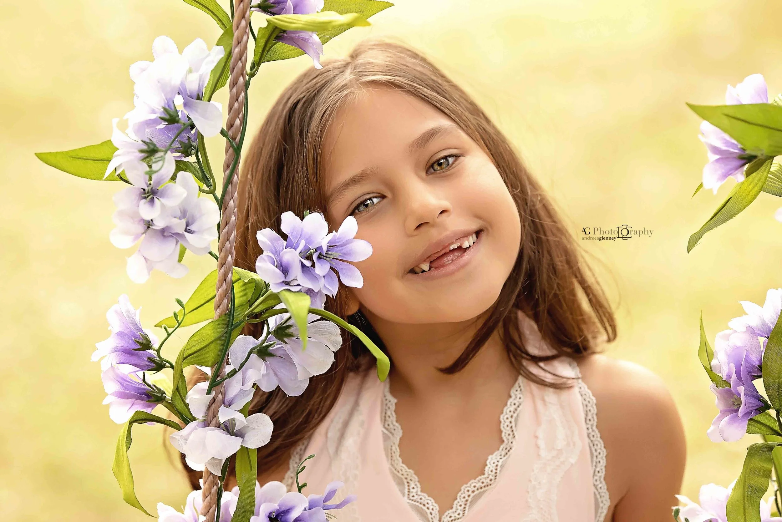 Girl sitting on a swing wrapped with flowers and smiling to the camera in Harrington Park, New Jersey