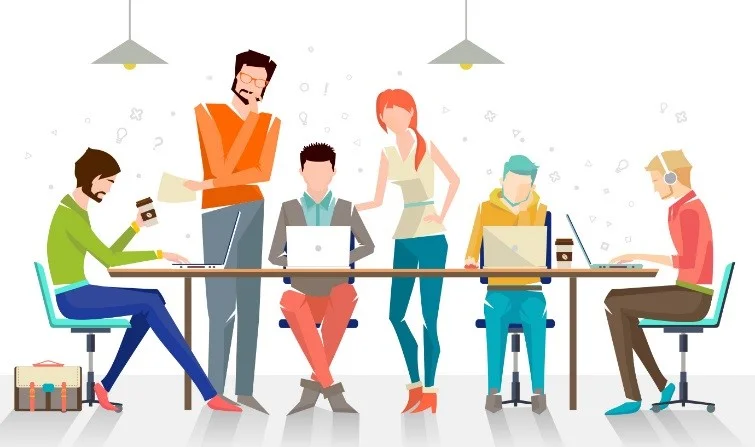 A team working on laptops on a long table