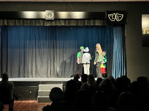 Children performing on stage during a theater play with audience watching.