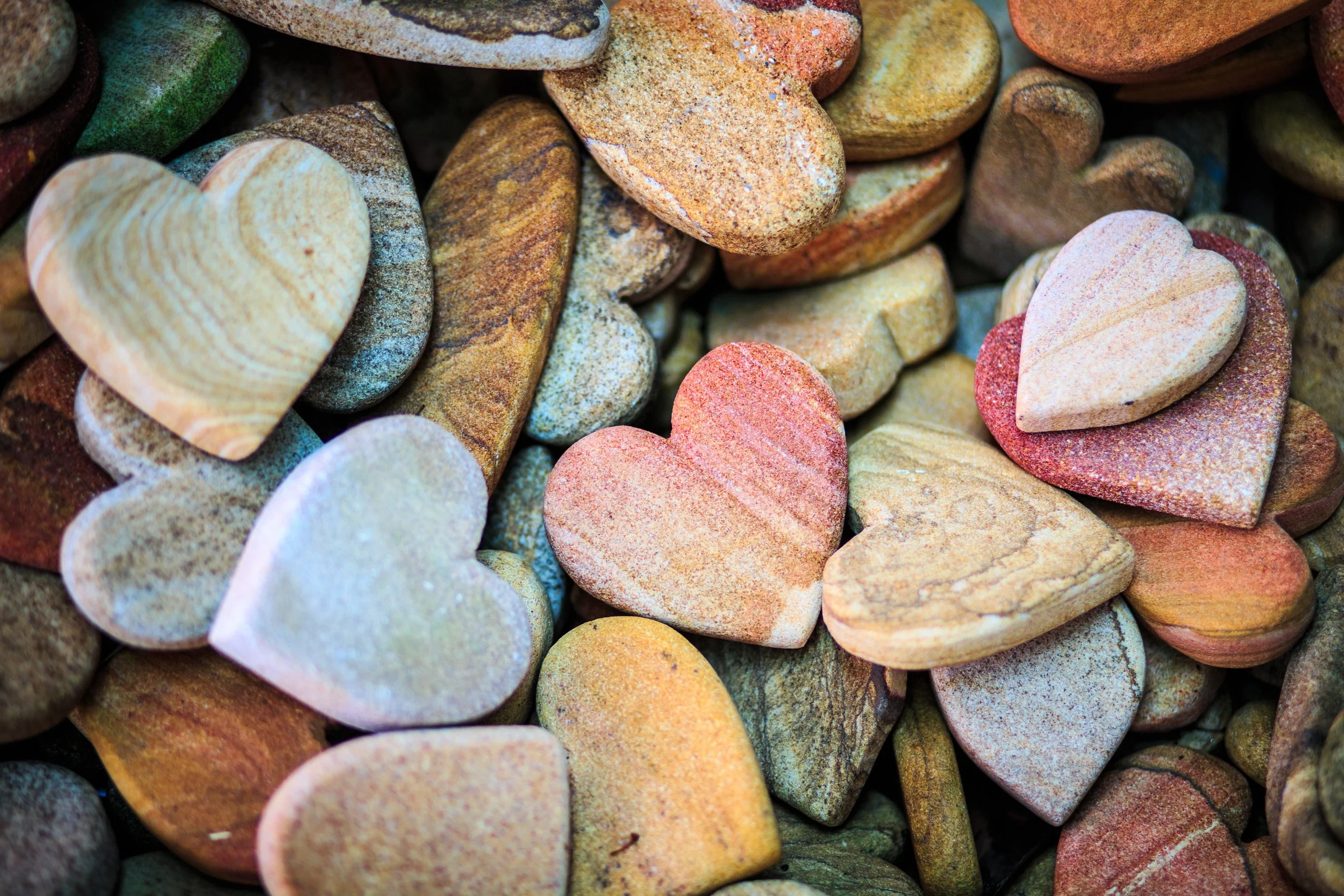 A pile of smooth heart-shaped stones in soft natural colours