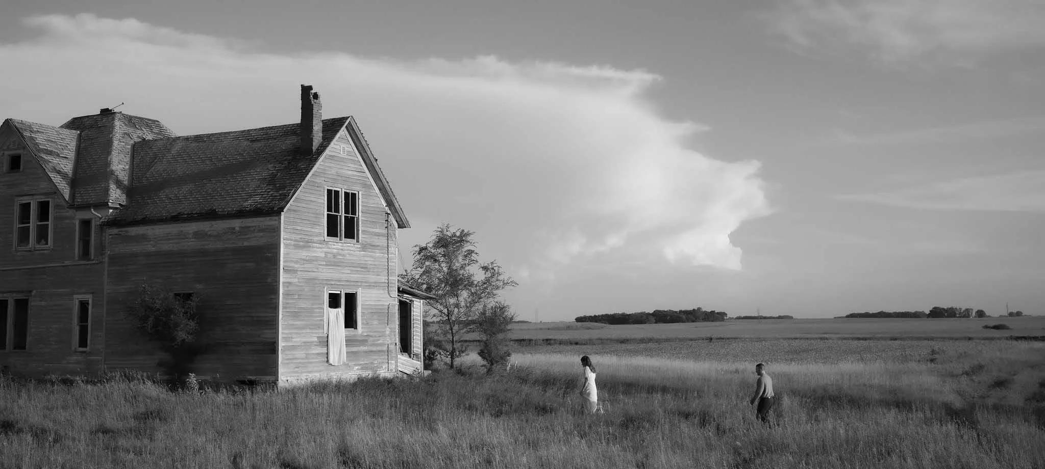 Engaged couple standing together at an abandoned house during an engagement photoshoot, captured in a candid and emotional moment.