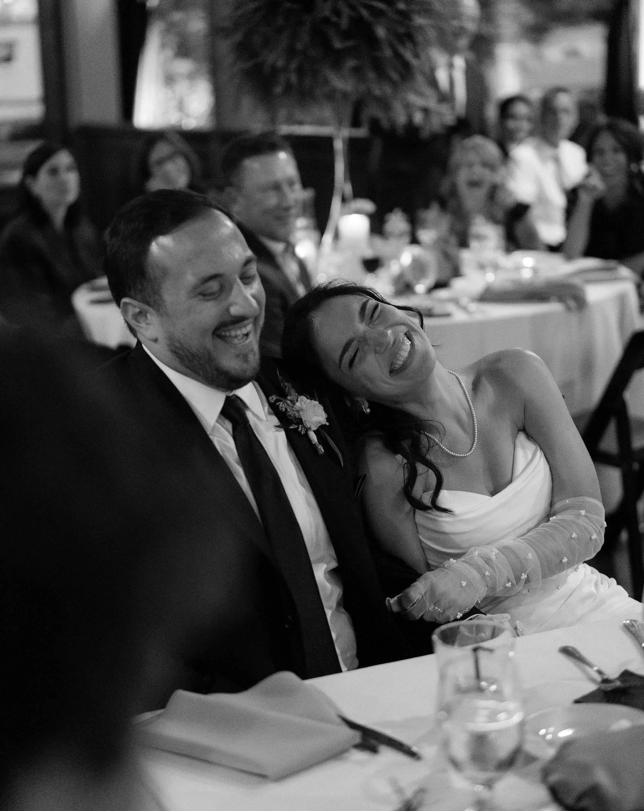 Candid wedding reception moment of a bride and groom laughing together, capturing real emotion and joy