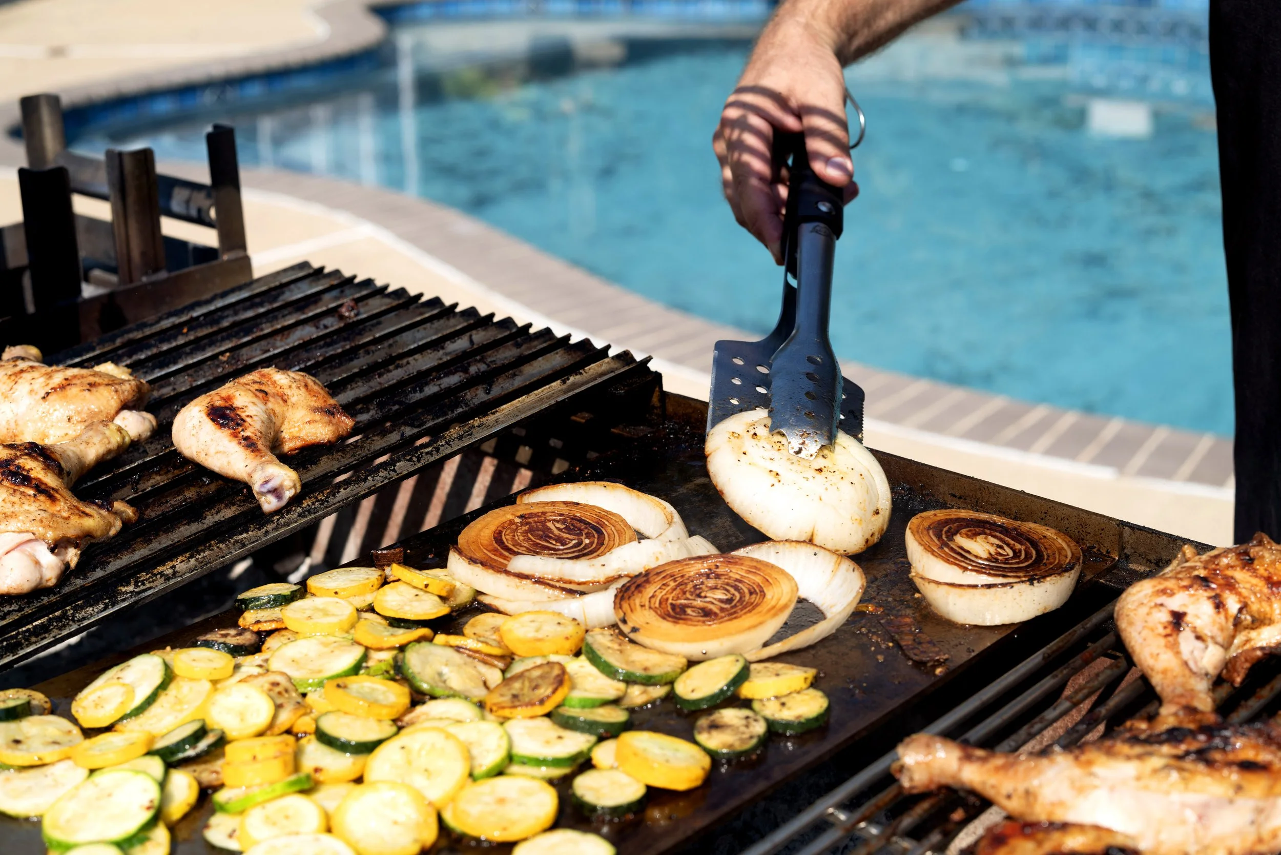 chicken grilling on the V-channel grate next to vegetables grilling on a plancha next to meat grilling on round bar grate
