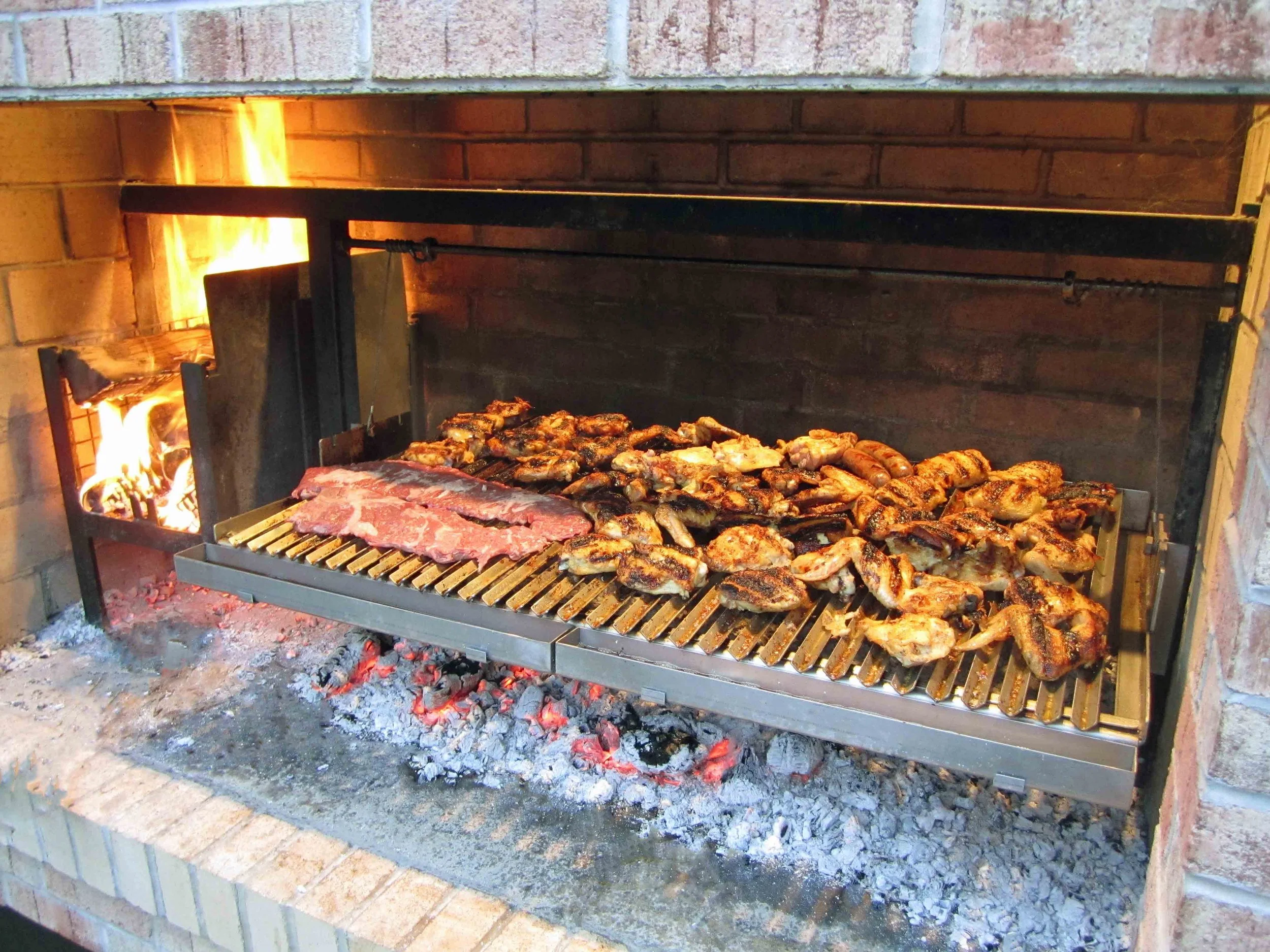 Argentine grill cooking multiple meats over glowing wood embers