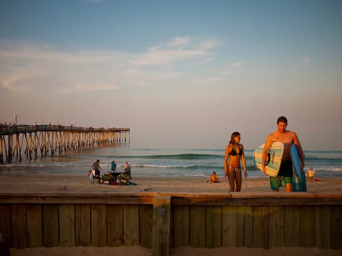 USA. Kill Devil Hills, North Carolina. 2010. A couple packs up after a day of summer surfing near the Avalon Pier. The biggest swells won't arrive until fall. Since the '60s, when surfing made its way here, the sport has steadily become embedded in OBX culture, and pros from around the world come to sample the waves.