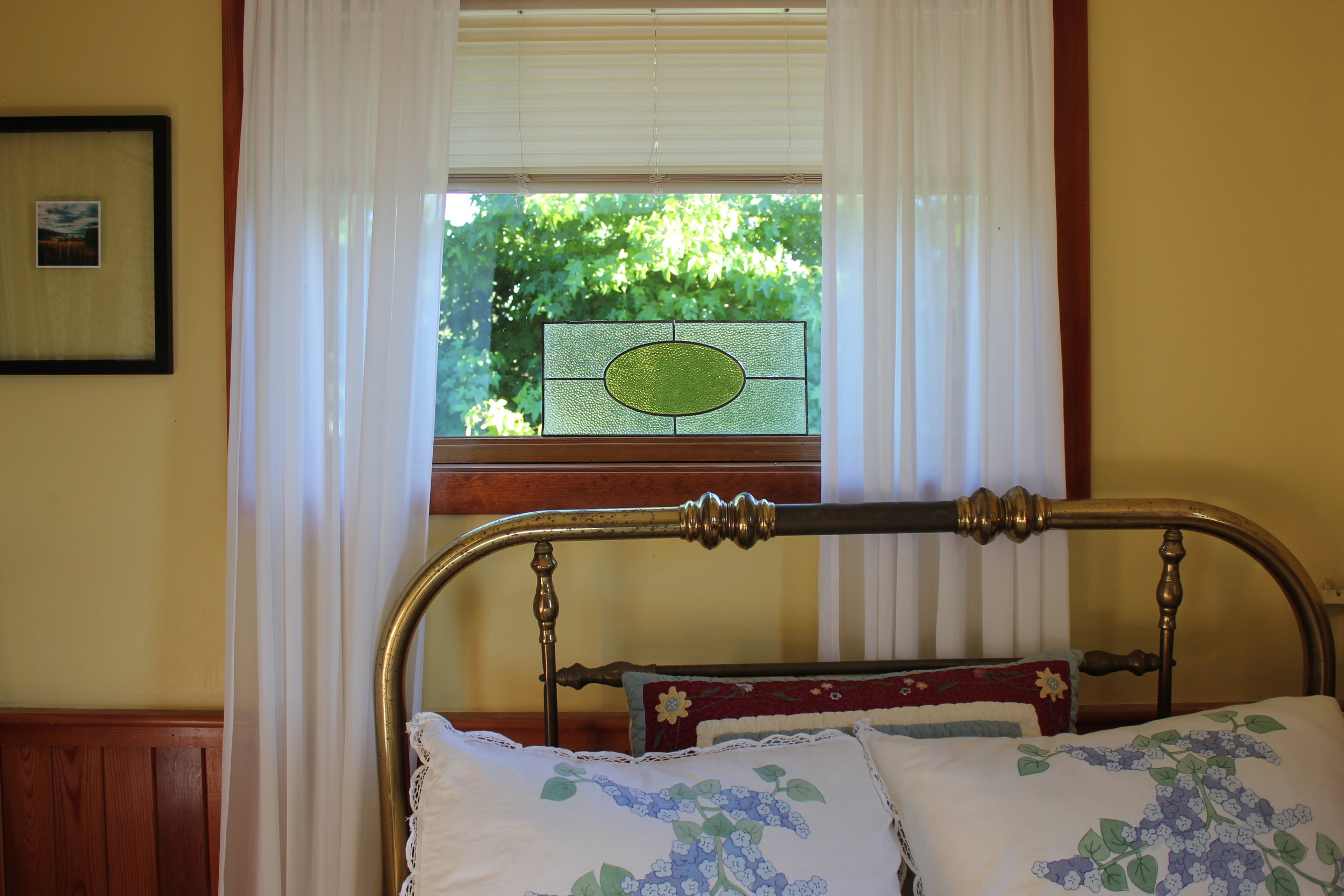 plum nelli iron bed and stain glass window in antique washington farm house.JPG