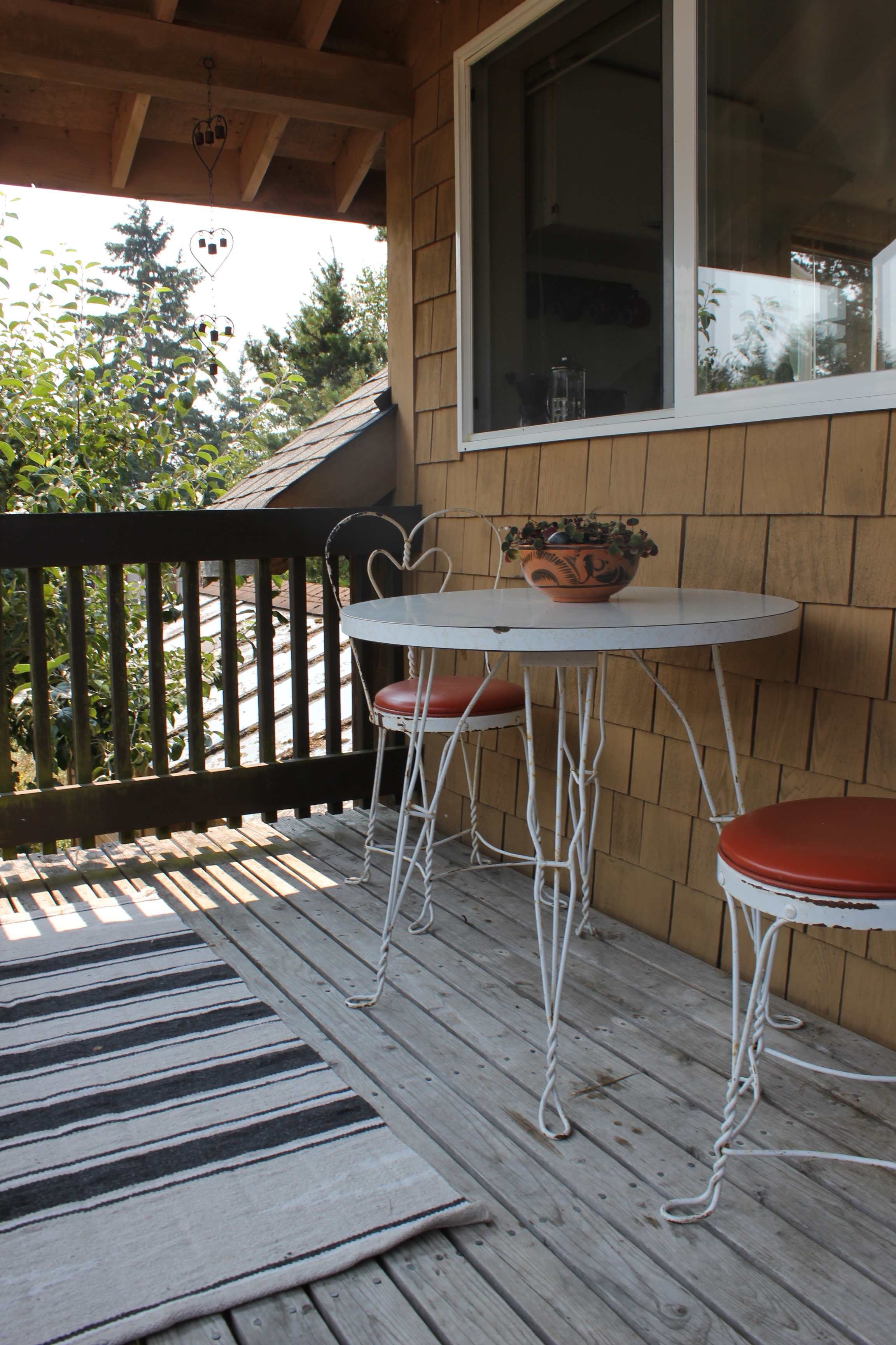plum nelli apartment porch with vintage chairs plants and handwoven rug.JPG