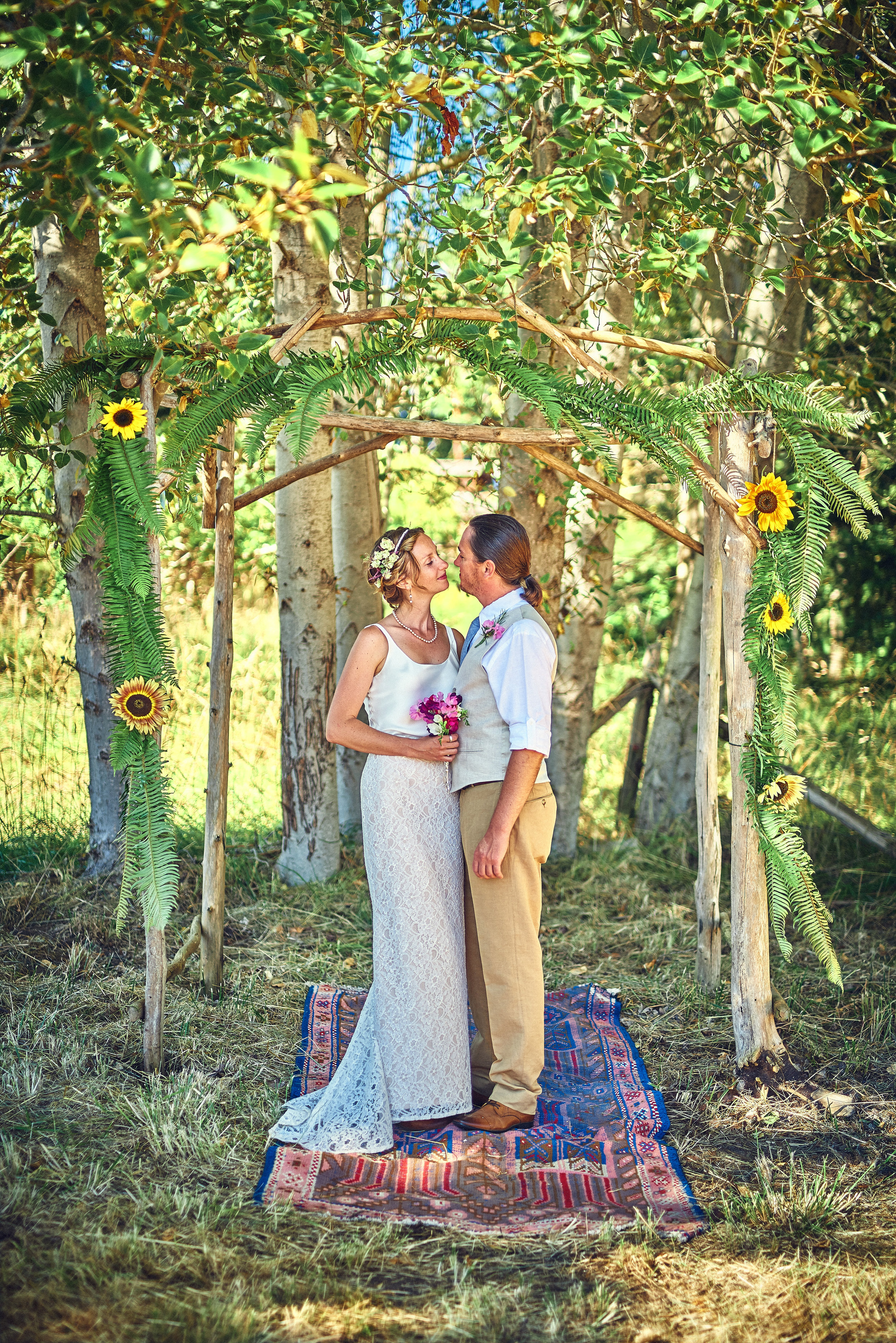 plum nelli farm wedding arbor with ferns and sunflowers and woven rug.jpg