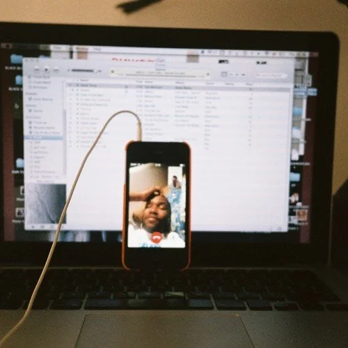 Frank Ocean on a iPhone, cell phone plugged into his laptop.