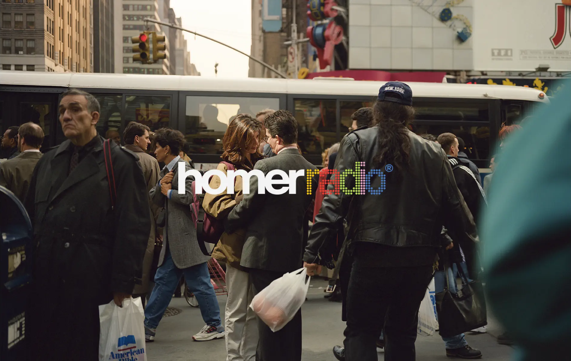 New York by Philip Lorca di Corcia. A photo of a couple locking eyes in a loving embrace while standing in the middle of a bustling New York City crosswalk. A man in the foreground has a bag from the American Bible Society. Show Banner Art.