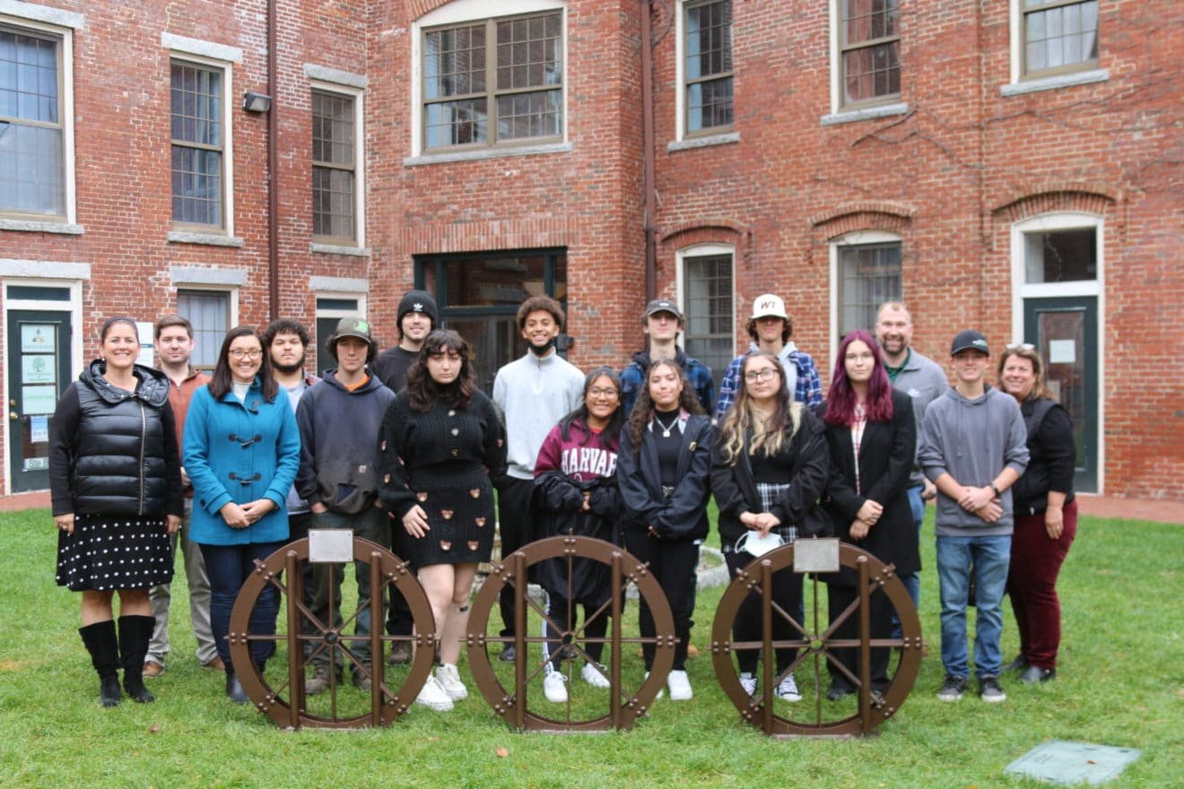 Former and current students in Whitter Tech's Metal Fabrication:Welding, Advanced Manufacturing, and CAD Drafting, Whittier Tech instructors, and City of Amesbury officials gathered to view bike racks in a water wheel design..jpg